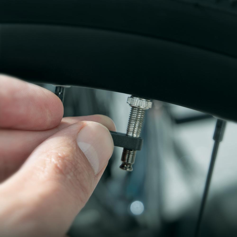 Hand befestigt SKS Clik-Valve Adapter für Pumpenköpfe am Fahrradventil. Präziser und sicherer Ventilwechsel.