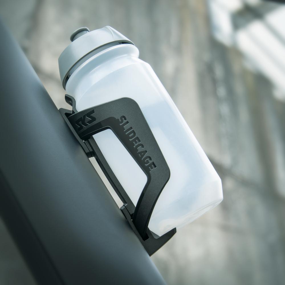 SKS Slidecage schwarzer Flaschenhalter aus Kunststoff mit transparenter Flasche am Fahrrad, seitliche Entnahme.
