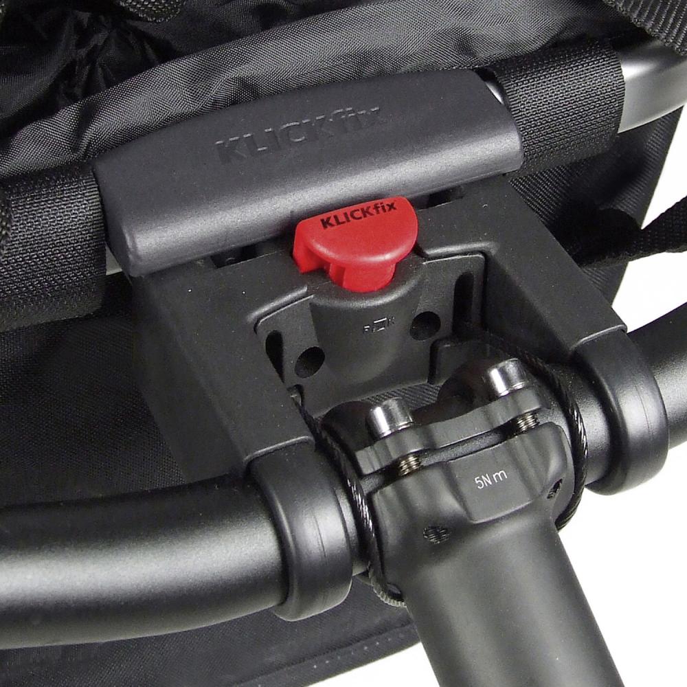 Schwarze KLICKfix Fahrradkorb- und Fahrradtaschen-Halterung am Lenker mit rotem Entriegelungsknopf.