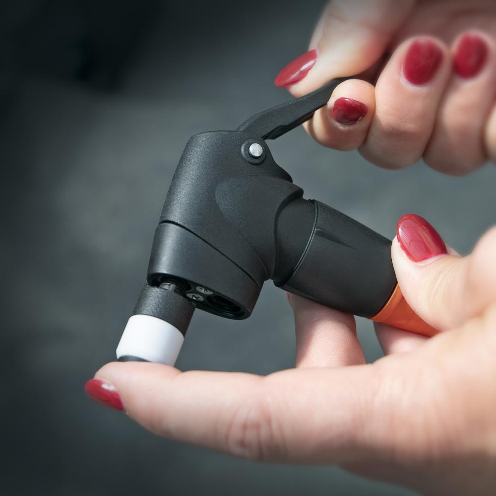 Hände halten SKS Clik-Valve Adapter für Fahrradpumpen, zeigt einfachen Ventilwechsel, Präzision und Qualität.