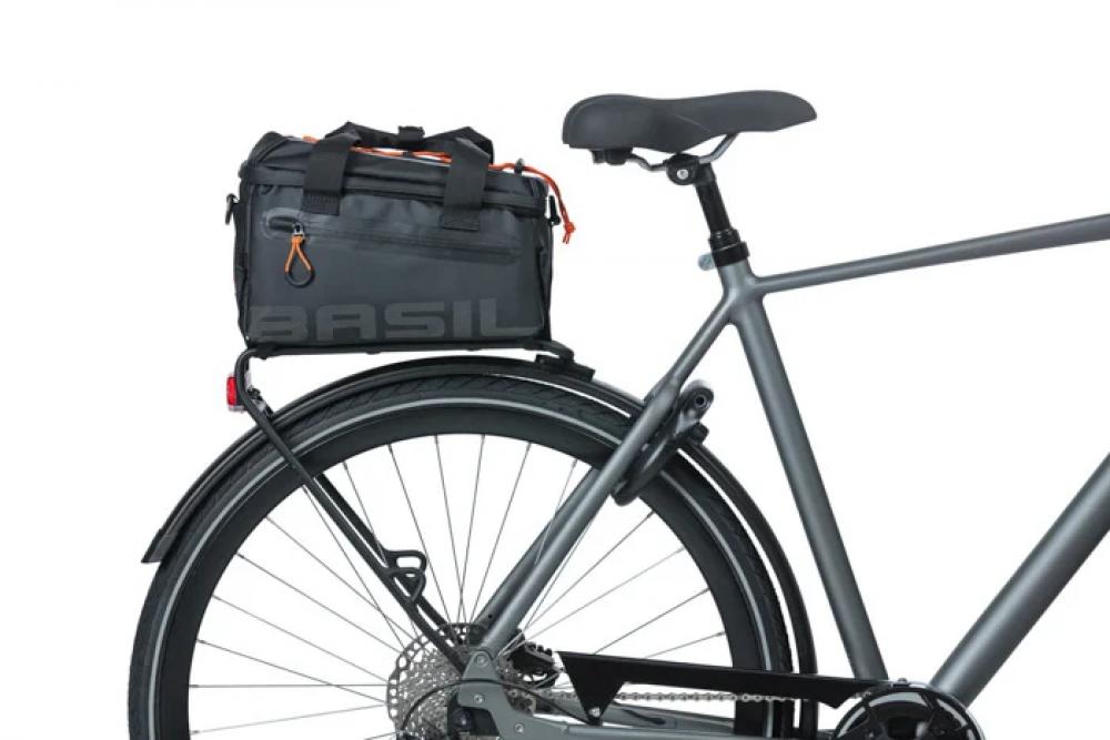 Basil Miles Tarpaulin Gepäckträgertasche schwarz-orange auf grauem Fahrrad-Heckträger. Wasserdichte Fahrradtasche mit Rollver