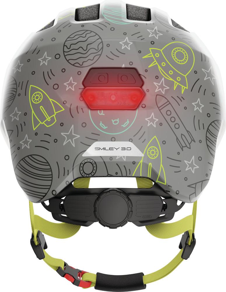 Abus Kinderhelm Smiley 3.0 LED, graues Weltraum-Design mit Raketen, Planeten und leuchtendem Rücklicht.