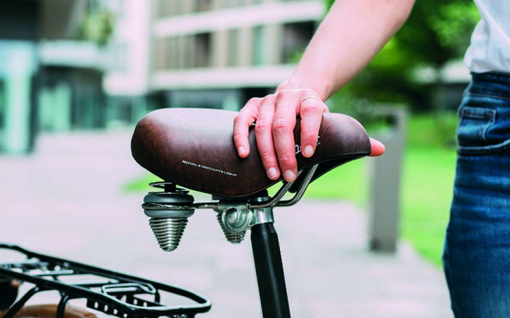 Brauner Selle Royal Drifter Fahrradsattel mit Doppelfedern und Vintage-Design für Citybikes, eine Hand darauf.