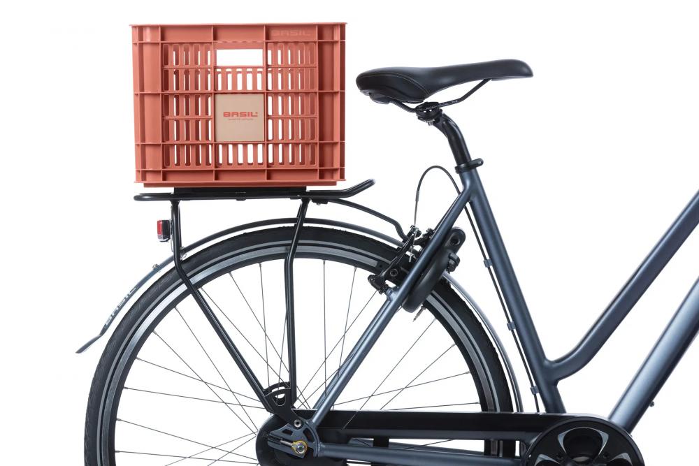 Rote Basil Crate M Fahrradkiste (29,5L, recycelter Kunststoff) auf Gepäckträger eines dunkelgrauen Fahrrads.
