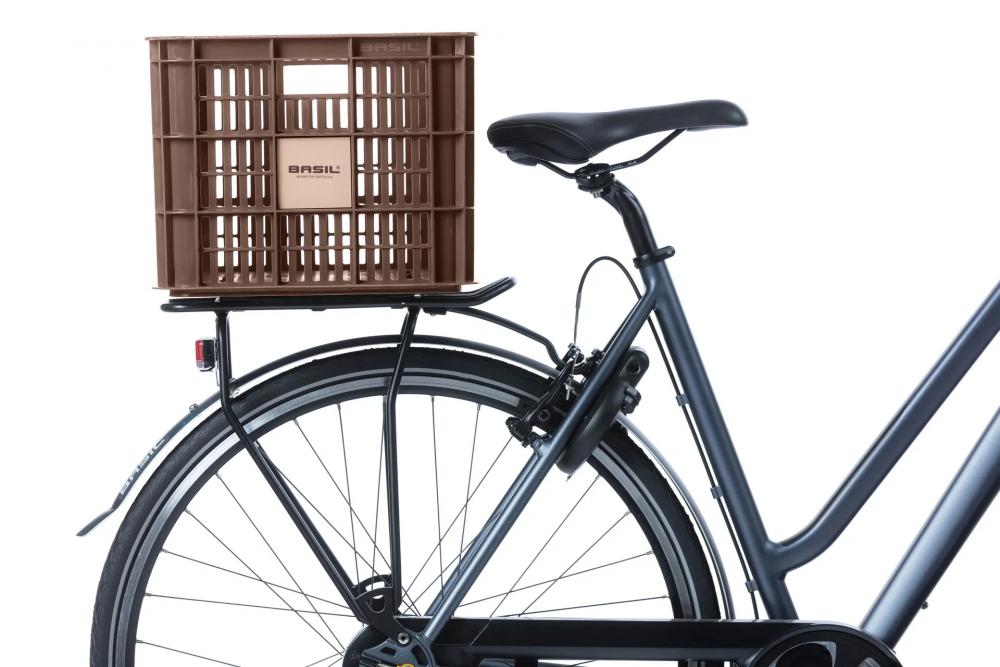 Braune Basil Crate L Fahrradkiste aus recyceltem Kunststoff (40L) auf dem Gepäckträger eines dunklen Fahrrads.