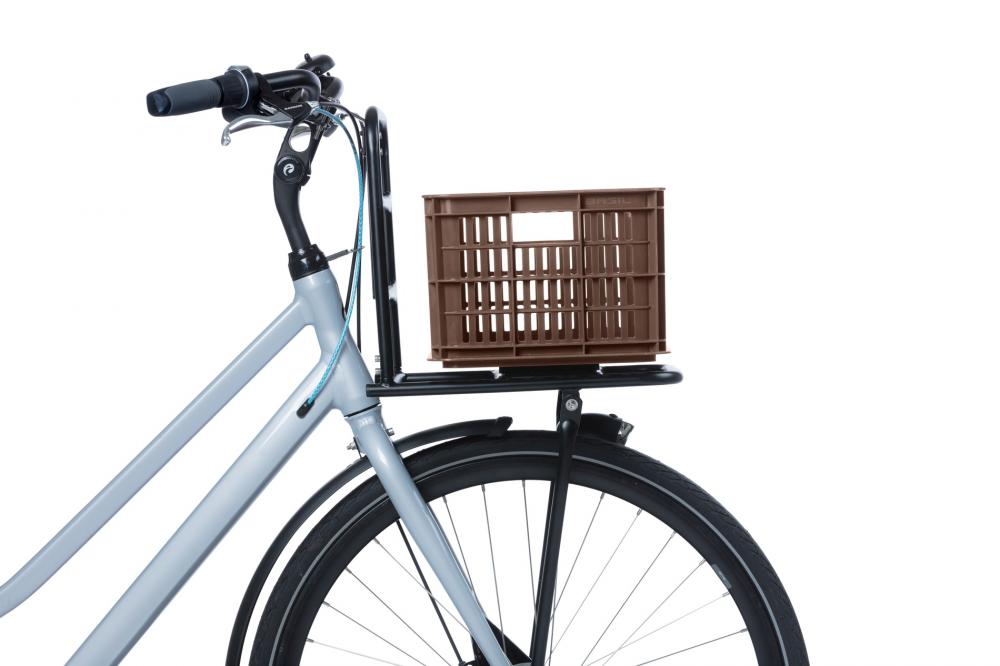 Braune BASIL Crate S Fahrradkiste (17,5L) aus recyceltem Kunststoff auf dem Frontträger eines grauen Fahrrads.