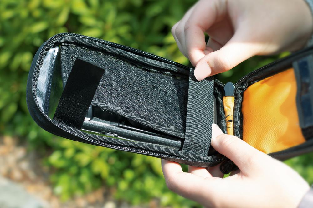 SKS COM/SMARTBAG: Person öffnet wasserfeste Smartphone-Tasche mit Klarsichtfenster und Stauraum für COMPIT-Halterung.