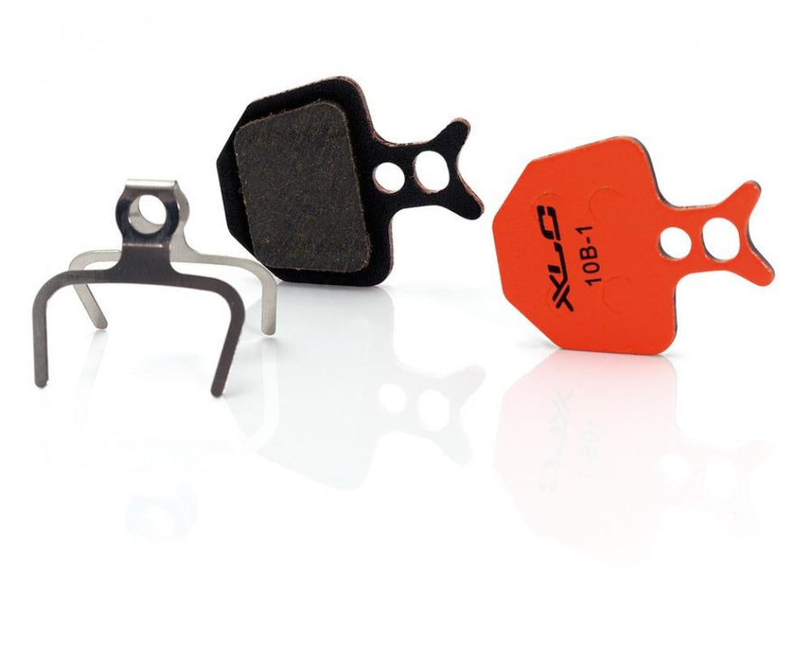 XLC Scheibenbremsbeläge BP-O16 Formula Oro Set mit orangefarbenem und schwarzem Belag und Feder auf weißem Grund.